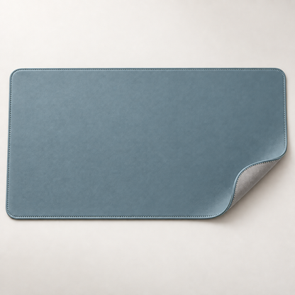 Velune Desk Pad in Soft Blue with a lifted corner showing the silver-grey reverse side.